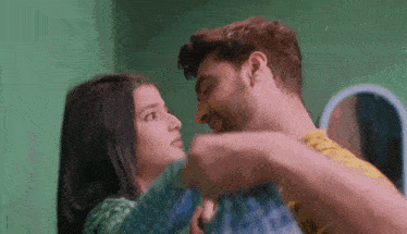 a man and a woman are kissing in a room .