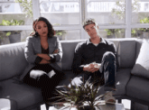 a man and a woman are sitting on a couch with their arms crossed