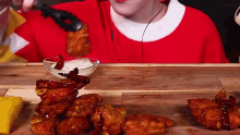 a woman in a red sweater is eating chicken wings