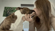 a woman is kissing a dog on the nose