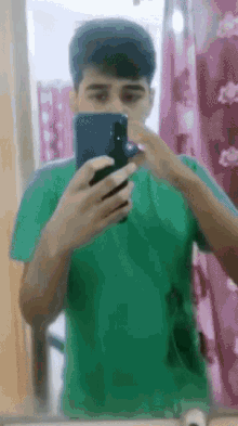 a young man in a green shirt is taking a selfie with his phone