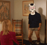 a man wearing a zebra mask stands in front of a woman sitting in a chair
