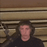 a man wearing headphones is sitting in front of a microphone in a room .