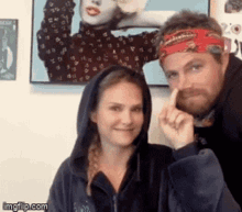a man and a woman are posing for a picture and the woman is wearing a hoodie