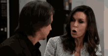 a man and a woman are talking to each other and the woman is making a surprised face .