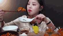 a woman is eating food with chopsticks and a white spoon .
