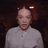 a woman wearing a striped shirt and hoop earrings is making a surprised face .
