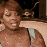 a woman in a blue tank top is sitting in a chair with her mouth open .