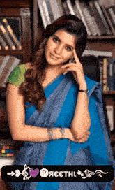 a woman in a blue saree is standing in front of a book shelf