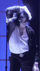 a man wearing a black jacket and a white shirt is dancing in front of a microphone