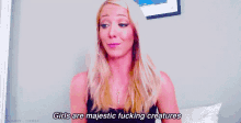 a woman is sitting on a bed with a key in her neck and says `` girls are majestic fucking creatures '' .