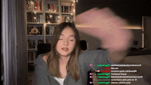 a woman 's face is visible in front of a bookshelf and a bunch of people are talking to her