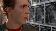 a man stands in front of a wall of posters that say beware of the perverts