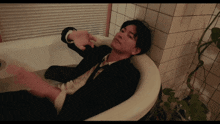 a man in a suit and tie is laying in a bath tub