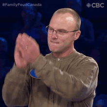 a man wearing glasses is clapping his hands in front of a cbc logo