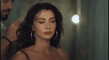 a woman wearing hoop earrings is getting her hair styled by a man