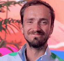 a man with a beard is smiling for the camera in front of a colorful background .