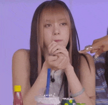 a girl with long hair is sitting at a table with a bottle of ketchup and a straw