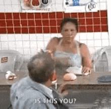 a man and a woman are sitting at a table in a restaurant and the woman is asking the man if he is this you .