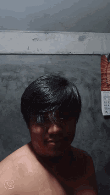 a man without a shirt is standing in front of a wall calendar