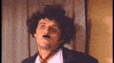 a man wearing a wig and a mustache is making a funny face .