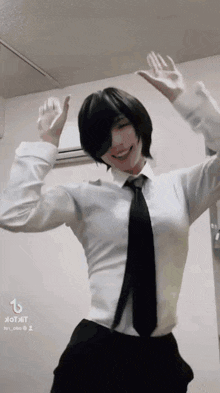 a woman in a white shirt and black tie is dancing with her hands in the air .