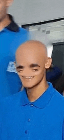 a bald man wearing a blue polo shirt is smiling and making a funny face .
