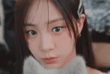 a close up of a woman 's face with a furry collar around her neck