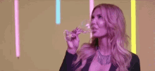 a woman is holding a wine glass in front of a neon light .