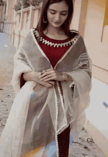 a woman wearing a red top and a white dupatta