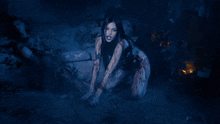 a woman with blood on her body is crawling in a dark room