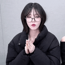 a young woman wearing glasses and a black jacket