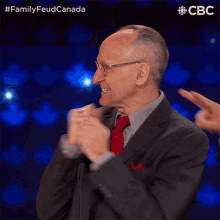 a man in a suit and tie is clapping his hands in front of a blue background with a cbc logo