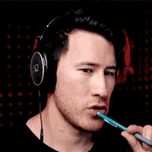 a man wearing headphones is holding a pen to his mouth