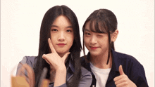 two girls are posing for a picture and one is giving the thumbs up