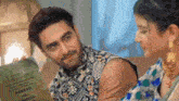 a man and woman are sitting next to each other and the man is holding a piece of paper that says armaan