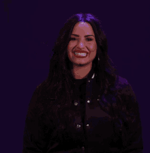 a woman in a black jacket is smiling and holding up a pixelated hand
