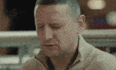 a man wearing a tan sweater is looking down with his eyes closed