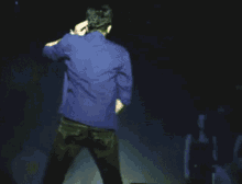 a man in a blue jacket is dancing on stage