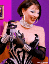 a woman in a black and silver dress is smiling and holding a glass
