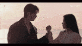 a man and a woman are holding hands in front of the ocean and netflix is visible in the corner