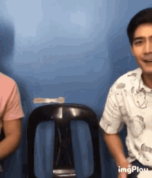 a man in a snoopy shirt sits next to a woman in a pink shirt ..