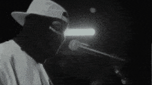 a man wearing a mask is singing into a microphone in a black and white photo .