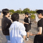 a group of young men are standing in a park with the words kpopismybias on the bottom