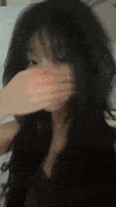 a close up of a woman covering her face with her hand .