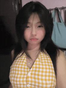 a girl wearing a yellow and white plaid shirt and a necklace