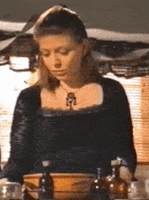 a woman in a black dress is standing in front of a bowl of liquid .