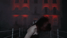 a woman with long red hair is dancing in front of a building