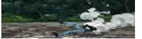 a man is laying on the ground in a field with smoke coming out of his mouth .