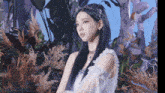 a woman with long black hair is wearing a white dress with ruffles